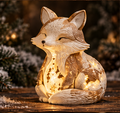 Cream and brown-gold seated Christmas fox with a curled tail and warm glowing star and tree details