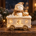 Front view of a glowing snowman train car with a gold-tone hat, scarf, wheels and star-shaped openings.